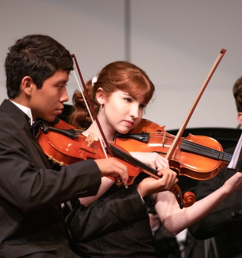 Dois violinistas se apresentando lado a lado