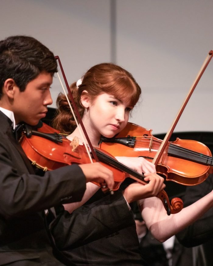 Dois violinistas se apresentando lado a lado