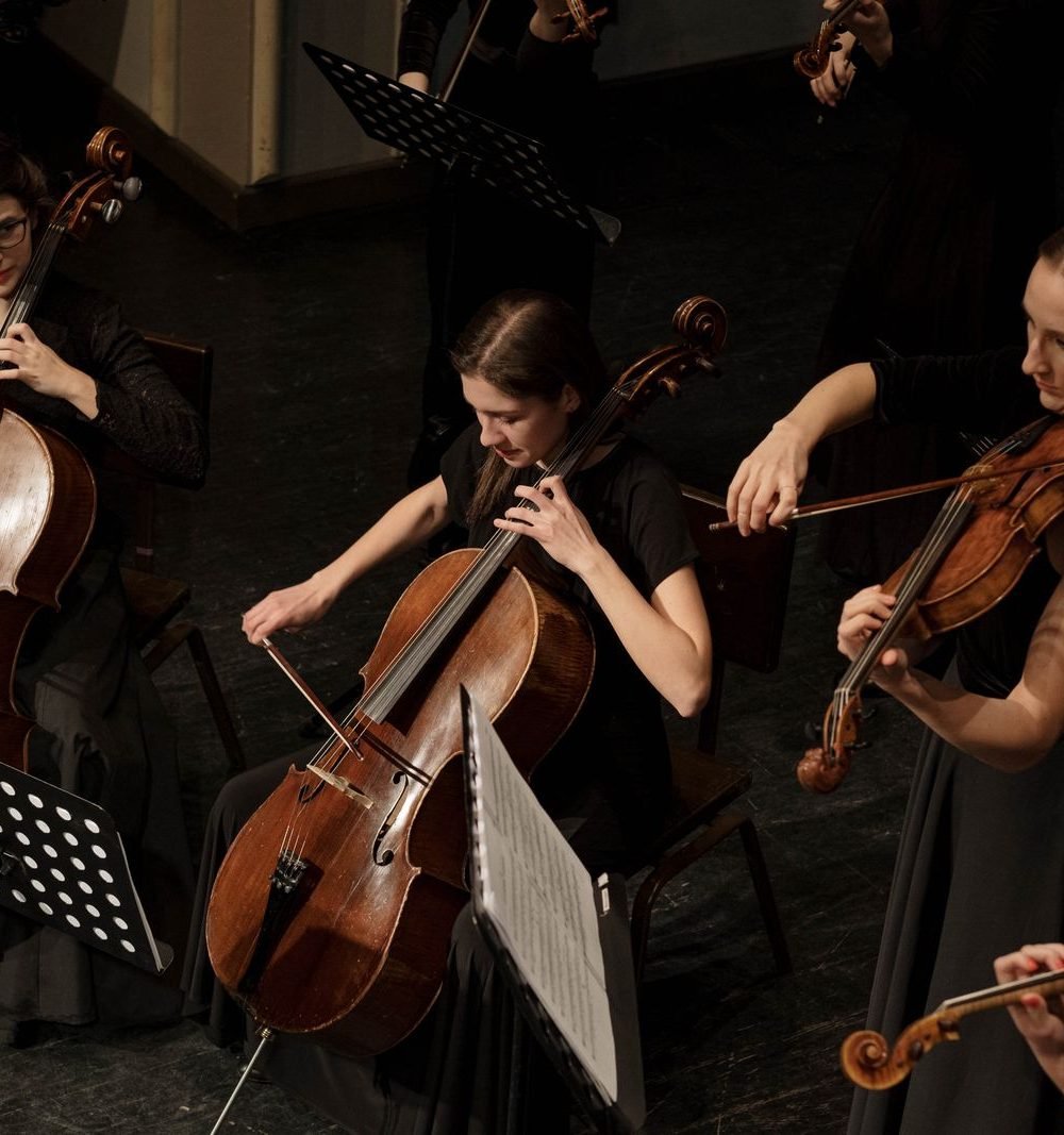 Musicistas tocando violoncelo e violino em conjunto orquestral