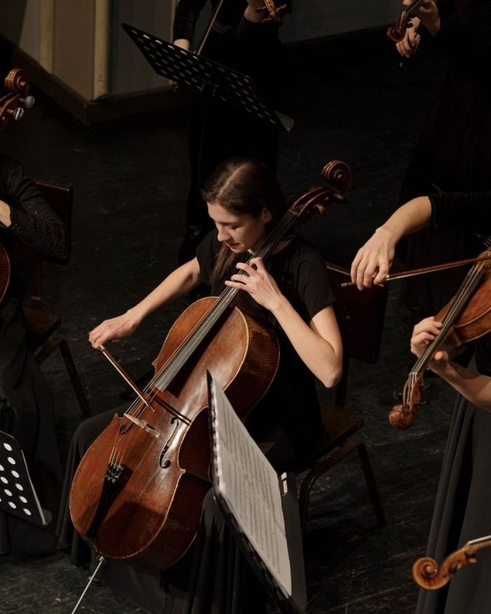 Musicistas tocando violoncelo e violino em conjunto orquestral