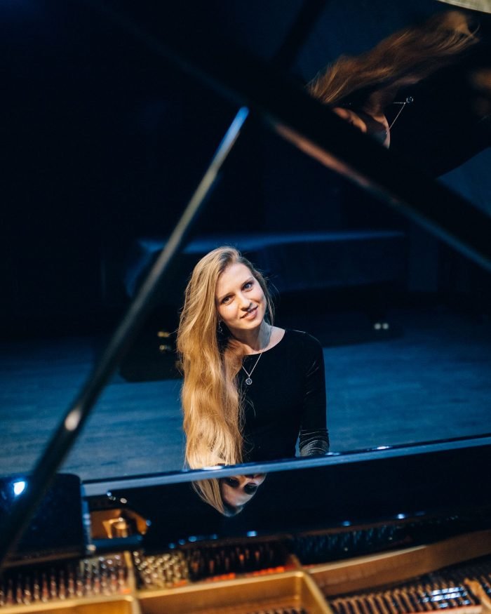 Vocalista se apresentando ao piano de cauda em palco