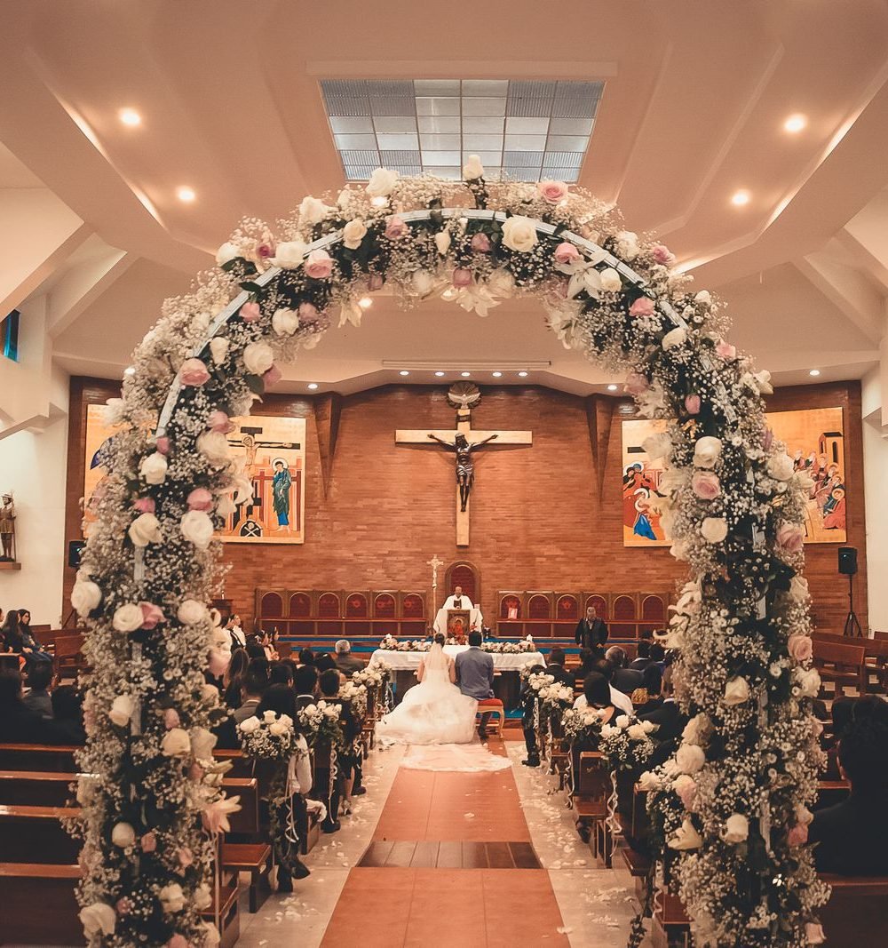 Cerimônia de casamento em igreja com arco floral e corredor central