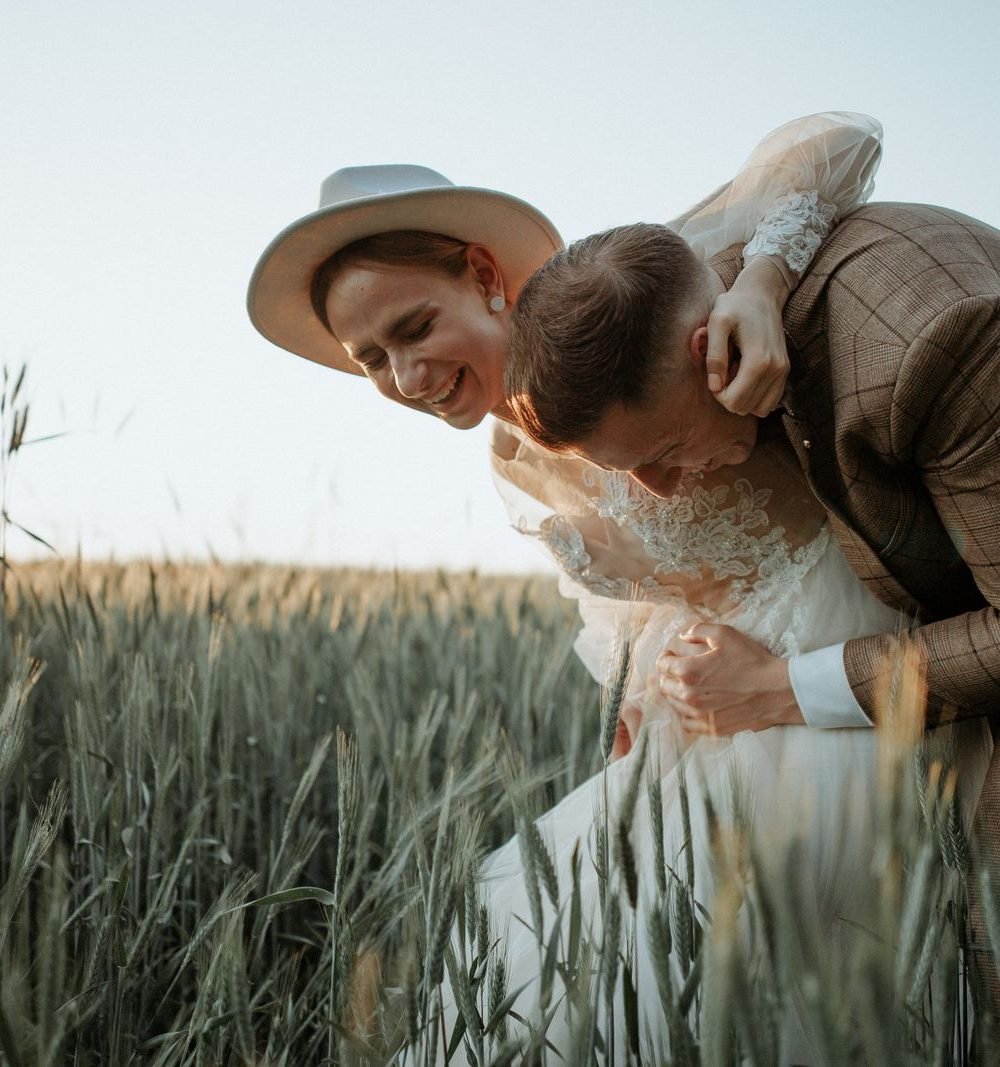 Casal sorridente em campo ao entardecer