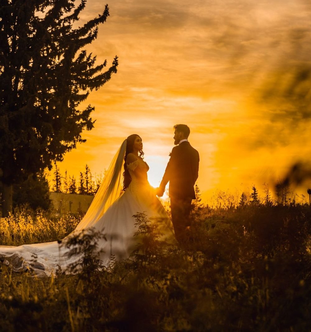 Noivos de mãos dadas durante pôr do sol dourado