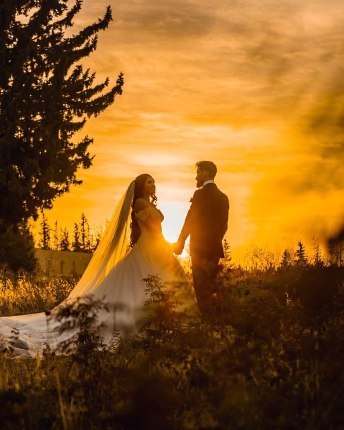 Noivos de mãos dadas durante pôr do sol dourado